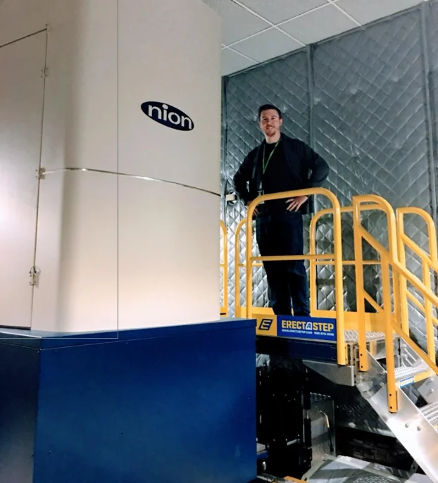 Kevin Roccapriore standing beside a Nion electron microscope